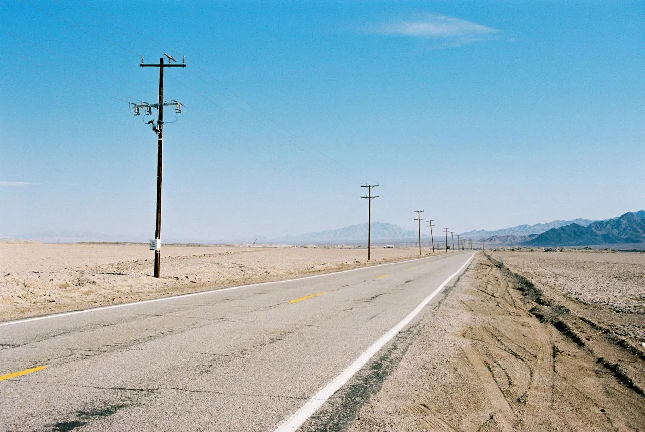 Desert highway stretching toward distant mountains under open sky