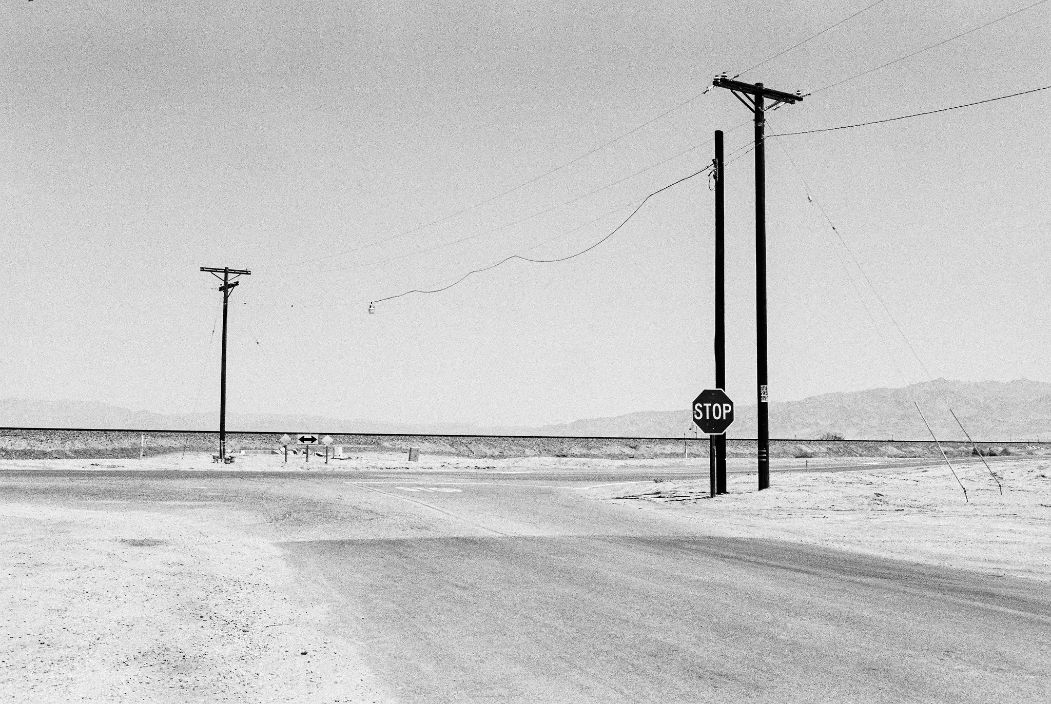 Stop sign and power lines at a desert crossroads in black and white